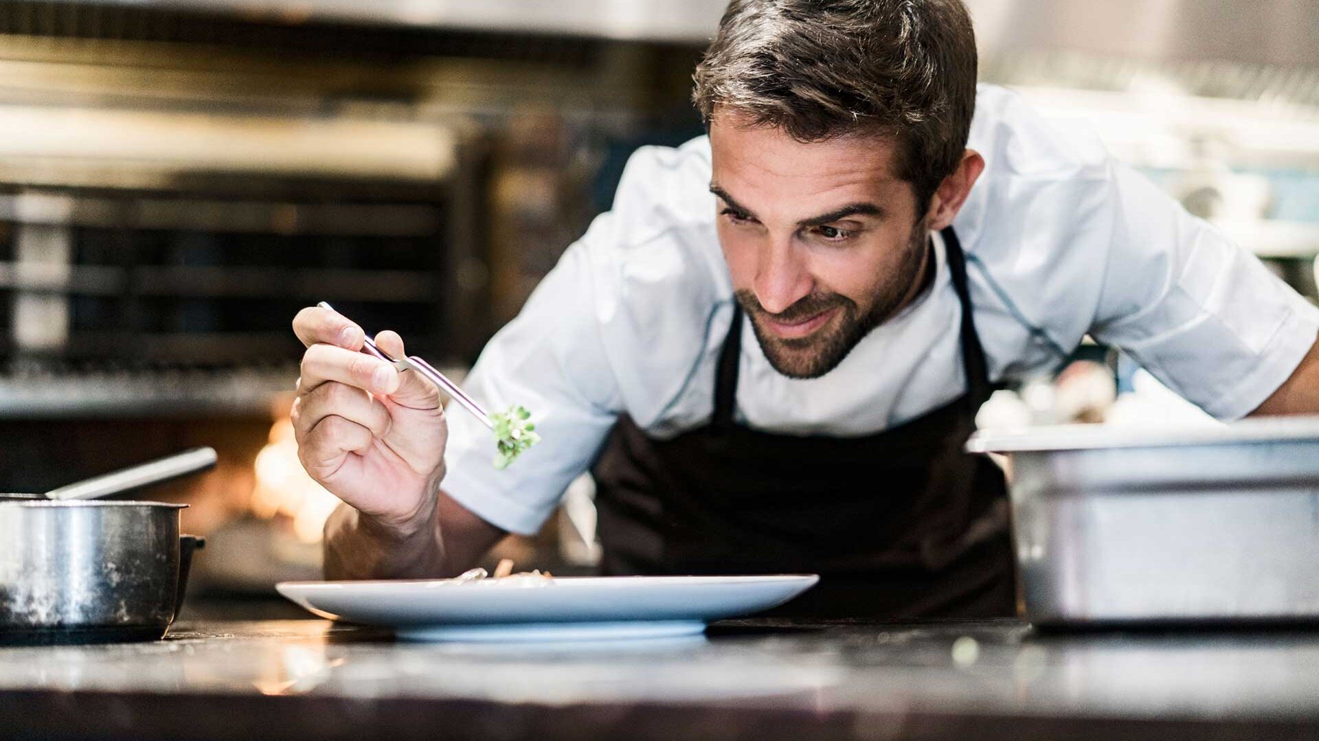 Koch richtet Essen auf Teller an