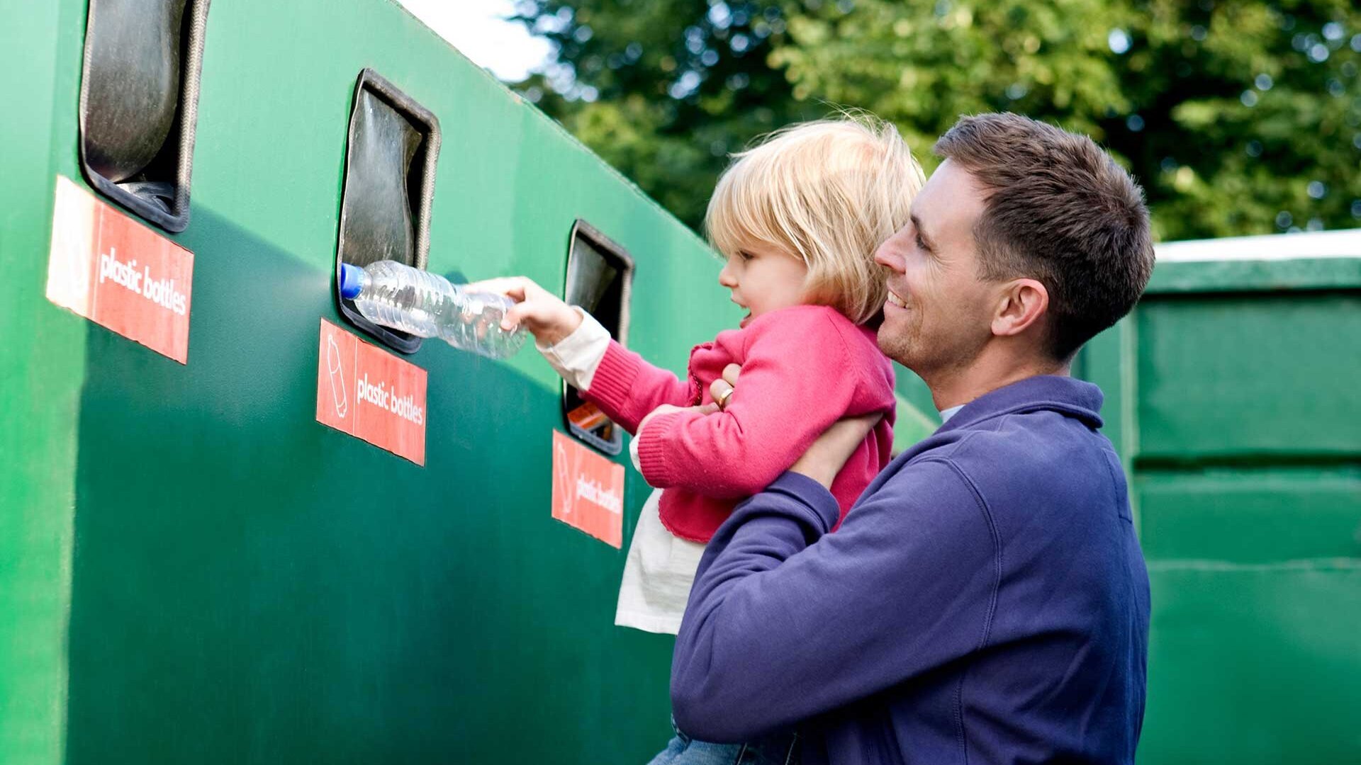 Vater recycelt mit seiner Tochter Flaschen am Container Vater zeigt Tochter, wie man Plastikflaschen recycelt