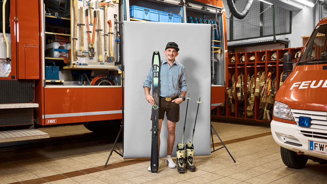 Martin in his lederhosen with skis in the fire station.