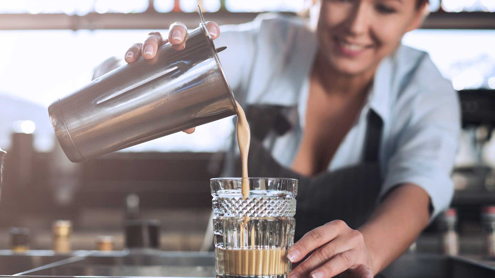 Bartenderin gießt Cold Brew Cocktail in Glas